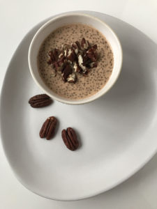 A bowl of Chia and pecan porridge with three pecan nuts on one side