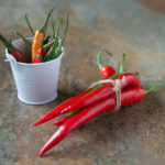 two bunches of chilli peppers one in a small white bucket