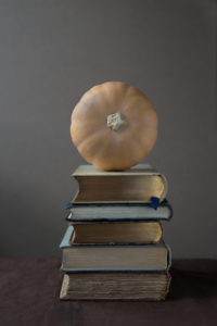 A squash sitting on a pile of books