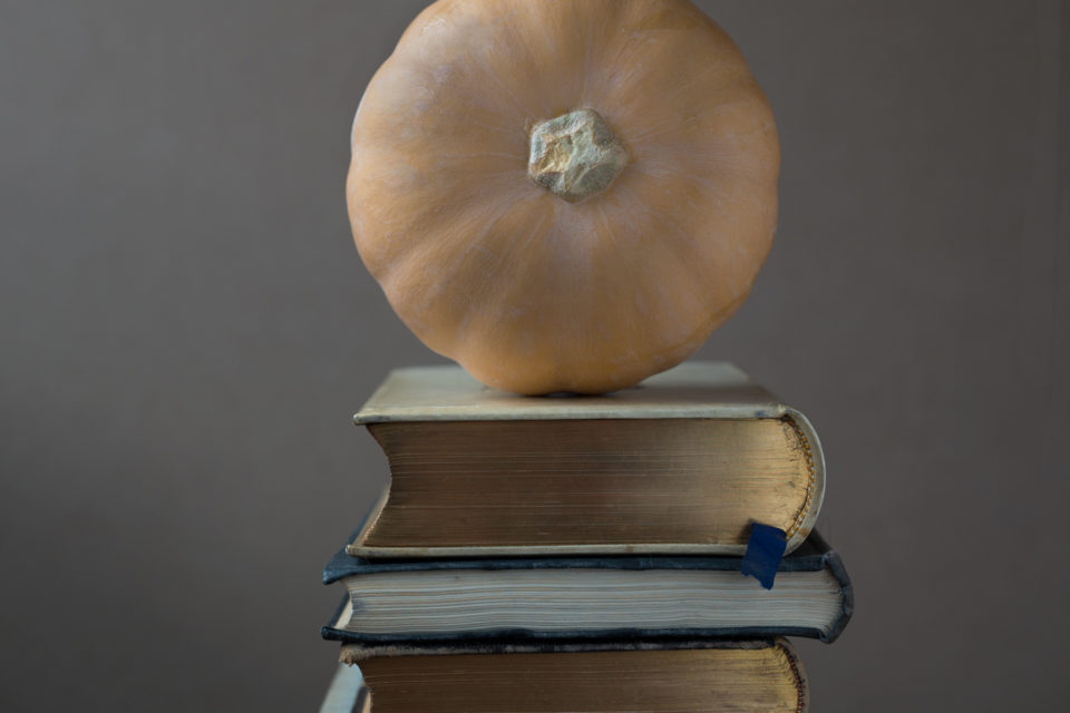 A squash sitting on a pile of books